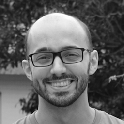 Homme souriant avec lunettes, cheveux courts, en noir et blanc.