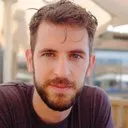 Homme barbu regardant sur le côté dans un cadre intérieur.